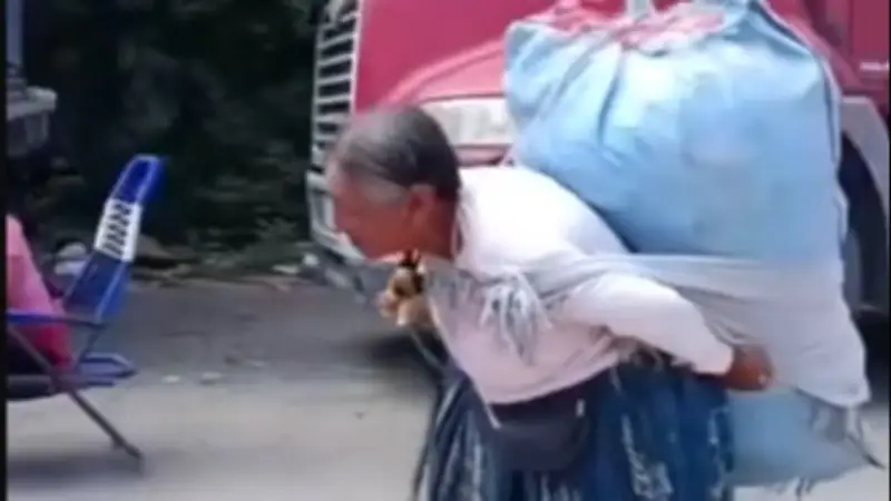 Adulta mayor cruza un bloqueo en Caranavi cargando su mercadería para seguir trabajando